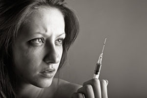 young woman contemplating syringe